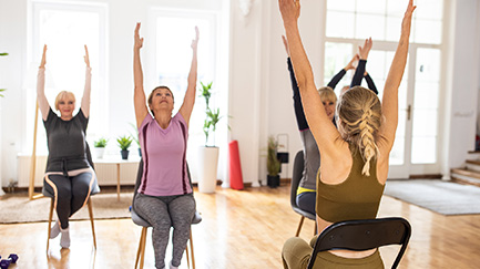Four women participate in chair yoga.