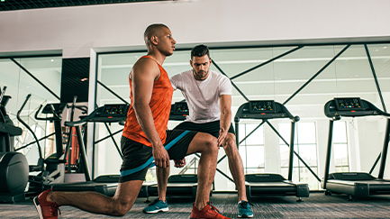 Person being instructed doing a lunge in the gym