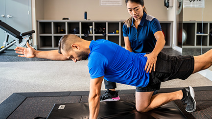 Man stretching assisted by a physical rehab clinician.