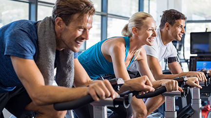Three people riding exercise bikes at a gym. 