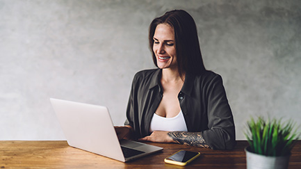 A woman sits in front of a laptop.