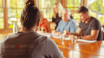 A woman sits alone across the table from smiling people.