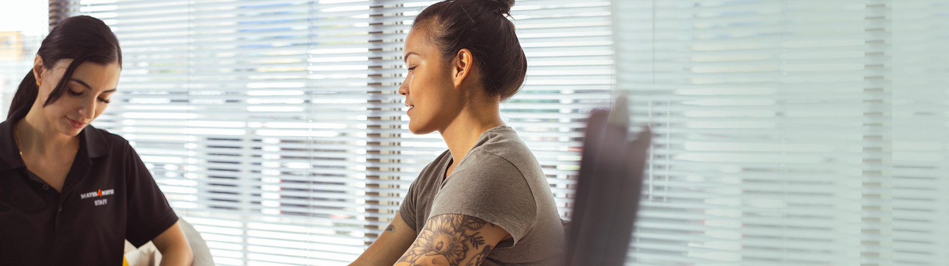 Female veteran sitting in a clinical appointment with a clinician writing notes.