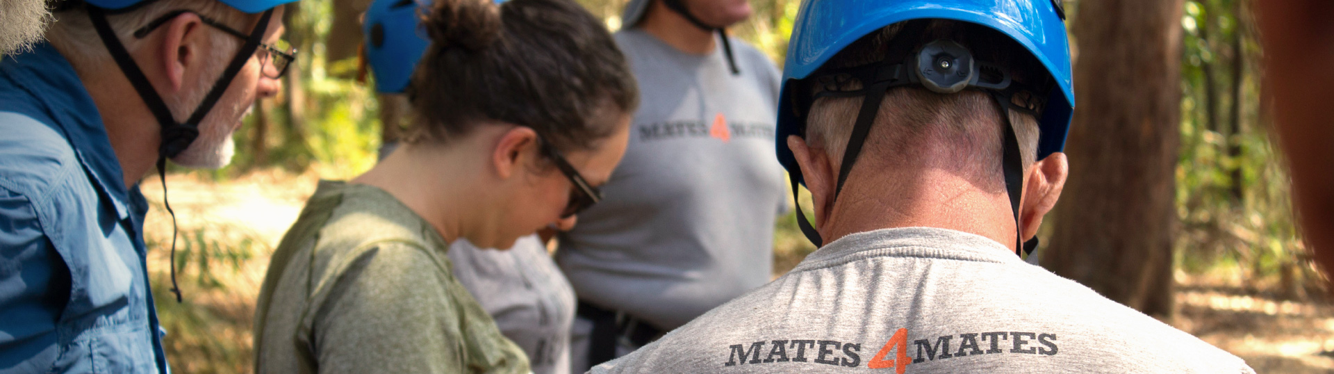 Group of people outdoors gearing up with helmets and harnesses.