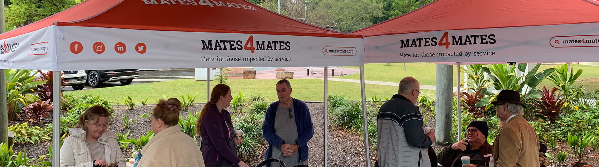 People standing underneath Mates4Mates gazebos talking together